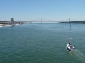 A picturesque view of a sailboat cruising along the waterway, with a stunning bridge in the background — perfect for showcasing scenic sailing adventures.