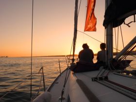 A couple enjoys a serene sunset while sailing, creating a perfect romantic atmosphere on the water.