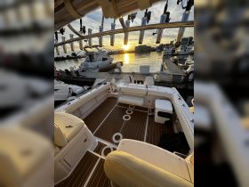 Interior view of a well-equipped boat with comfortable seating and a scenic sunset visible through the windows, perfect for relaxing on the water.