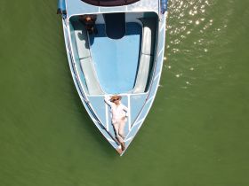 A person relaxes on the bow of a boat, enjoying the sun and the serene waters — a perfect moment for leisure on the water.