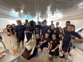 A cheerful group poses together in snorkeling gear aboard a boat, ready for an exciting underwater adventure. Perfect for group outings and marine exploration.