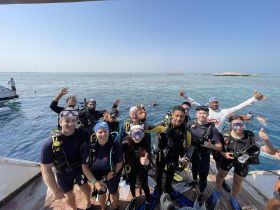 A lively group of divers poses for a photo before their underwater adventure, showcasing the excitement of snorkeling in beautiful waters.
