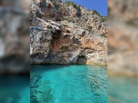 A stunning view of a rocky coastline with a cave entrance, surrounded by crystal-clear turquoise waters — an ideal spot for exploration and adventure.