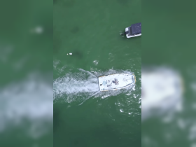 Aerial view of a boat cruising through clear waters, showcasing its sleek design and movement.