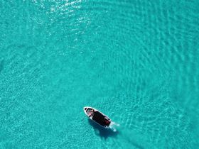 A stunning aerial view of a speedboat gliding through crystal-clear turquoise waters, perfect for showcasing boating adventures in tropical destinations.