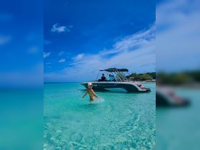 A child joyfully splashes in the crystal-clear waters while a boat is anchored nearby, capturing the essence of a fun-filled day on the water.