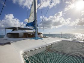 A stunning view of a catamaran sailing on sparkling waters, showcasing its sleek design and the beauty of the open sea.