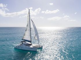 A stunning aerial view of a catamaran sailing through sparkling turquoise waters, showcasing the beauty of a perfect day on the sea.