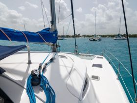 A close-up view of the deck of a catamaran, showcasing its sleek design and vibrant blue ropes against the backdrop of turquoise waters and other vessels.