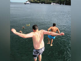 Two friends leap into the water while others swim nearby, capturing the excitement of a fun day on the water — perfect for adventure seekers and group outings.