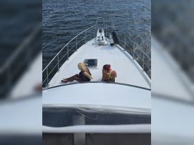Two friends relax on the bow of a boat, enjoying the sun and water — a perfect moment for a fun day out on the water.