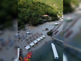 Aerial view of a vibrant beach scene with kayaks lined up along the shore, sun loungers, and people enjoying various activities — a perfect destination for water sports and relaxation.