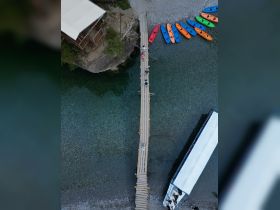 Aerial view of a wooden pier with people enjoying the scenic surroundings, alongside colorful kayaks ready for adventure. Perfect for water sports enthusiasts and family outings.