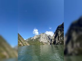 A breathtaking view of towering mountains reflected in calm waters, showcasing the stunning natural beauty of the landscape — perfect for eco tours or scenic boat rides.