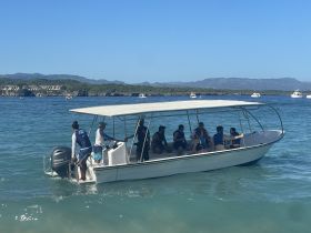 A lively group enjoys a boat ride, equipped with life jackets, in clear waters — perfect for adventure and exploration.