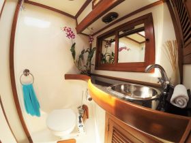 A well-appointed boat bathroom featuring elegant wooden finishes, a sink, and decorative plants, perfect for comfort on the water.