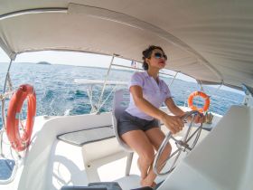 A woman confidently steers the helm of a boat, showcasing the interior space and the thrill of navigating the open waters.
