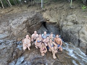A joyful group of friends poses together on rocky terrain near the water, capturing a fun moment during their beach adventure.