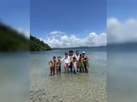 A joyful family gathers in shallow water at a beautiful beach, enjoying a sunny day together — perfect for creating lasting memories on a tropical getaway.