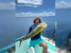 A proud angler holds up a large fish caught during a fishing trip, showcasing the thrill of ocean fishing adventures.