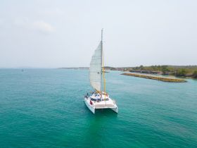 A stunning aerial view of a catamaran sailing through crystal-clear waters, showcasing the beauty of maritime adventures.