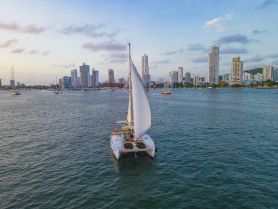 A stunning aerial view of a catamaran sailing through the waters of Cartagena, with a backdrop of modern skyscrapers — perfect for showcasing sailing adventures in vibrant urban settings.
