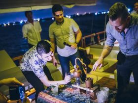 A lively group enjoys a cocktail-making experience on a boat at night, showcasing the fun and social atmosphere of a boat party.
