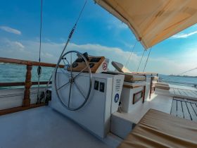 A well-equipped helm area of a sailing boat, showcasing the steering wheel and comfortable seating, perfect for navigating the open waters.