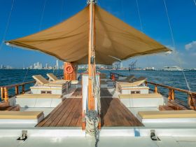A beautifully designed lounge area on a boat, featuring comfortable seating and shade, perfect for relaxing while enjoying views of the city skyline.