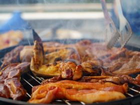 A close-up of a sizzling grill filled with a variety of meats, perfect for onboard barbecues and culinary experiences while enjoying time on the water.