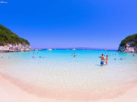 A vibrant beach scene with people enjoying the clear turquoise waters, perfect for swimming and island hopping adventures.