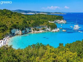 A stunning aerial view of a picturesque beach with crystal-clear waters, dotted with boats and sunbathers enjoying the sun — a perfect destination for summer adventures.