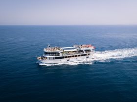 Aerial view of a spacious yacht cruising through open waters, showcasing its elegant design and perfect for group charters or leisurely outings.