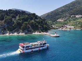 An aerial view of a lively boat cruising along a stunning coastline, perfect for island hopping adventures in crystal-clear waters.