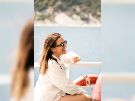 A joyful moment captured on a boat, showcasing a woman enjoying the ocean breeze and the beautiful scenery — perfect for highlighting fun experiences on the water.