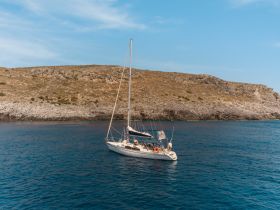 A picturesque sailboat anchored near a rocky coastline, showcasing the beauty of nautical adventures in serene waters.