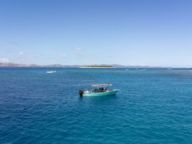 A small boat navigates the vibrant blue waters near a picturesque island, showcasing the beauty of a tropical getaway.