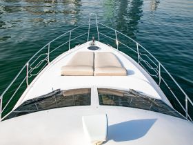 A stunning view of the front deck of a yacht, showcasing its sleek design and inviting seating area, perfect for relaxation on the water.