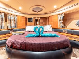 A cozy cabin interior featuring a round bed adorned with towel swans, perfect for a romantic getaway on the water.