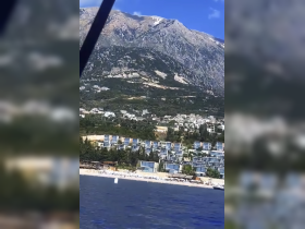 A stunning view of a mountainous coastline with beach resorts, showcasing the natural beauty of the area — perfect for vacation inspiration.