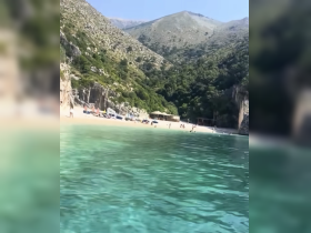 A picturesque beach scene with people enjoying the clear waters and stunning coastline, perfect for a day of relaxation and fun in the sun.