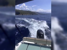 A scenic view from the back of a boat, showcasing the wake and beautiful coastline in the background, perfect for capturing the essence of a day on the water.
