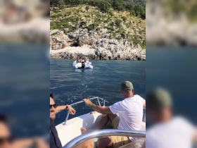 A lively group enjoys a day on the water, with a scenic rocky coastline in the background and another boat approaching, perfect for adventure and exploration.