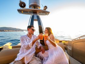 A couple enjoys cocktails while celebrating at sunset on a luxurious boat, creating the perfect romantic atmosphere for special occasions.