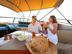 A couple enjoys cocktails and snacks aboard a luxurious boat, perfect for romantic getaways or special celebrations on the water.
