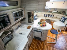 A beautifully designed boat interior featuring a spacious lounge area and a well-equipped kitchen, perfect for entertaining guests while on the water.