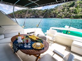 A beautifully arranged table featuring an assortment of snacks and drinks on a boat, perfect for a relaxing day on the water surrounded by stunning scenery.