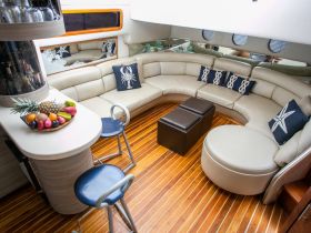A stylish interior view of a boat's lounge area featuring comfortable seating and a decorative fruit display, perfect for relaxing on the water.