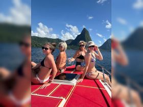 A group of friends enjoys a sunny day on a boat, with stunning mountain scenery in the background — perfect for memorable vacation moments.