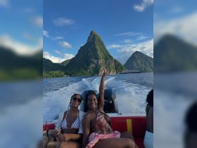 Two friends enjoy a fun boat ride with stunning island scenery in the background, capturing the essence of adventure and celebration on the water.